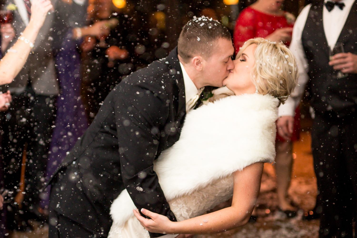 Newly married couple kissing in snow in front of Proximity Hotel